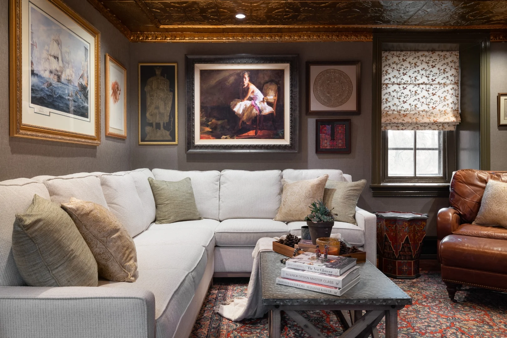 White sectional sofa beneath a gallery wall anchored by a large framed ballerina painting, with a zinc-top coffee table and a leather club chair in the Bucks County living room