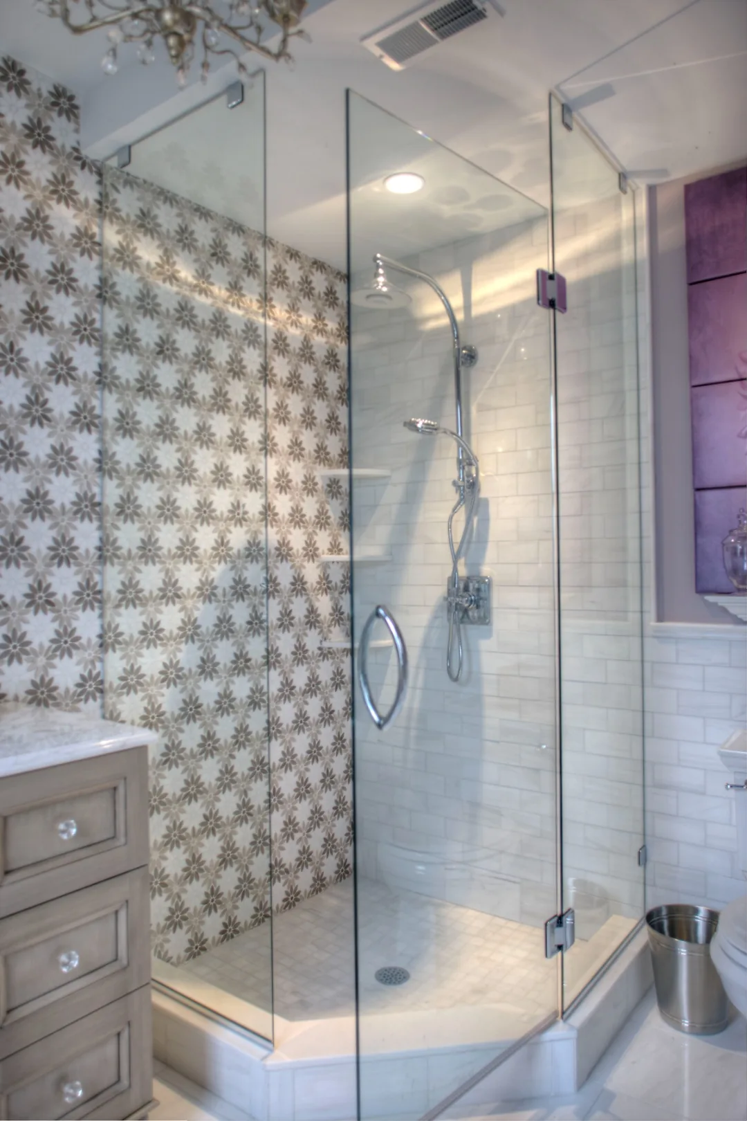 Cape May ensuite bathroom after renovation with a frameless glass corner shower, floral marble mosaic, marble subway tile, and a polished chrome rain shower