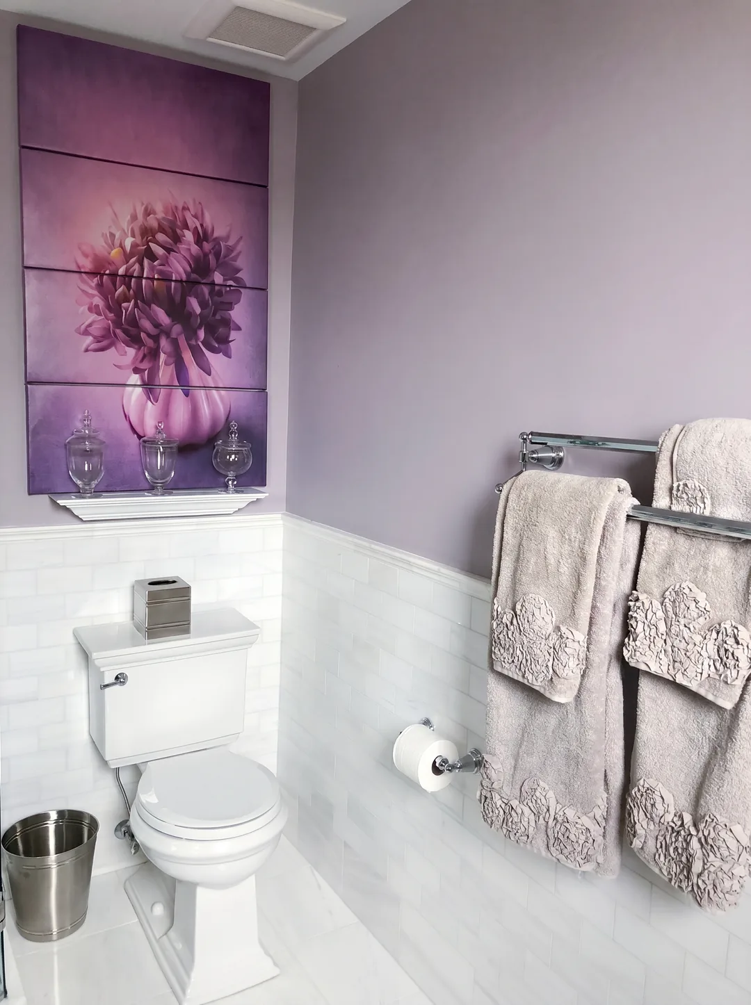 Toilet alcove in the Cape May ensuite with a purple peony triptych canvas, soft lavender walls, white marble subway wainscot, and textured grey towels