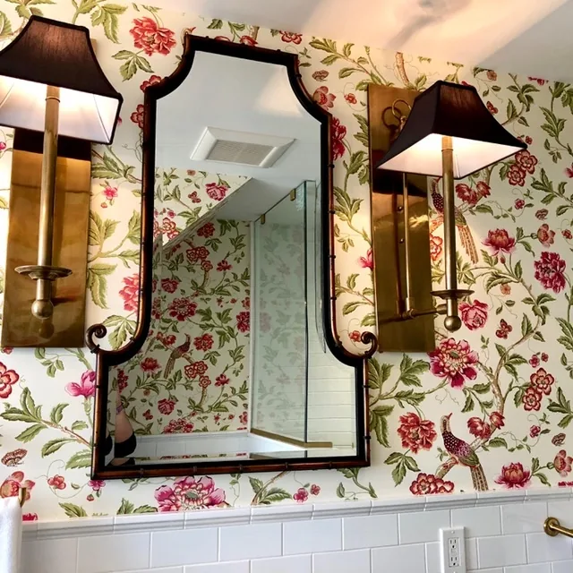 Brass bamboo-style mirror flanked by black-shade brass sconces on the pink-and-green floral chinoiserie wallpaper in the Cape May bathroom