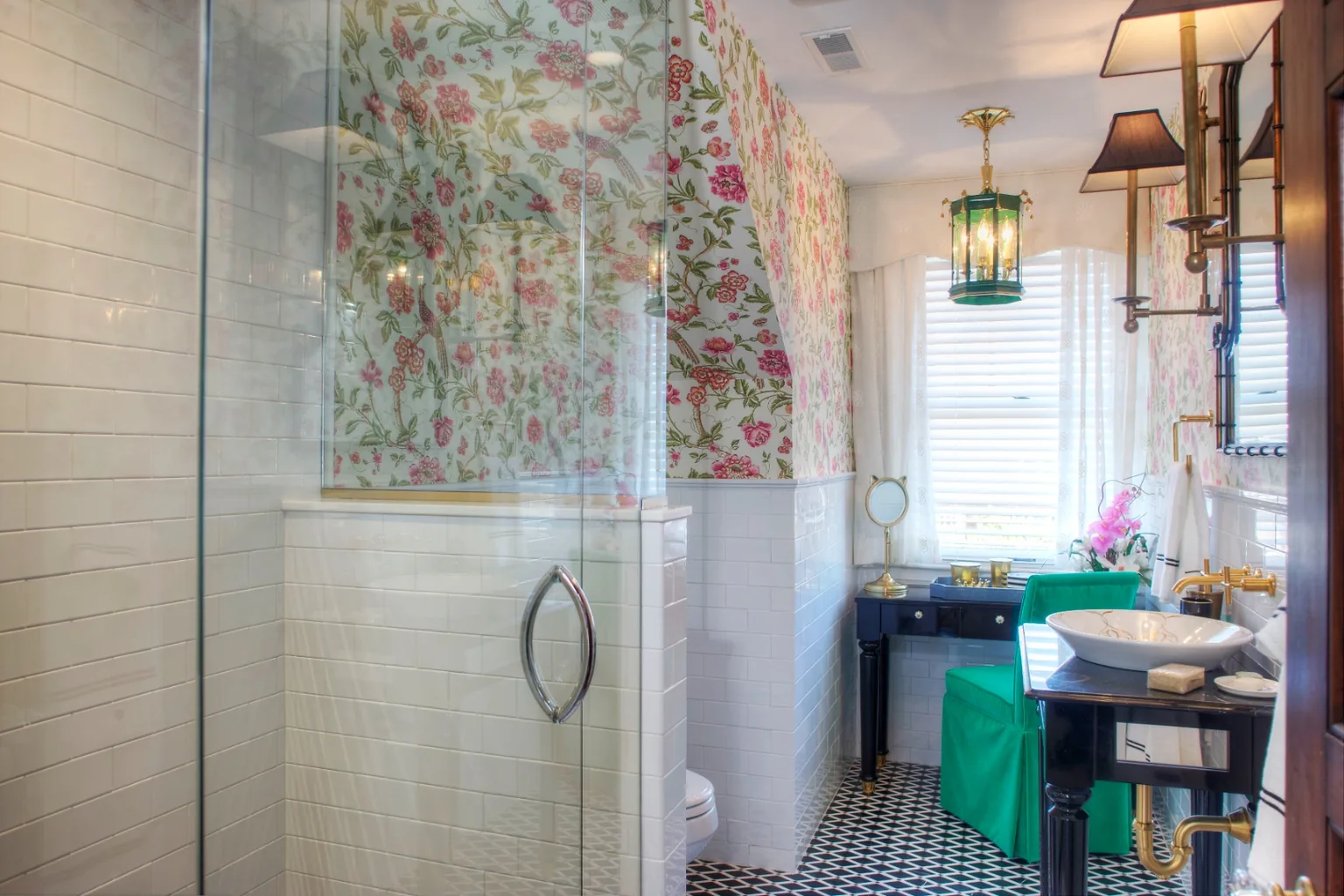 Cape May chinoiserie hall bathroom with pink-and-green floral wallpaper, white subway wainscot, a black lacquer vanity, frameless glass shower, and a green glass lantern