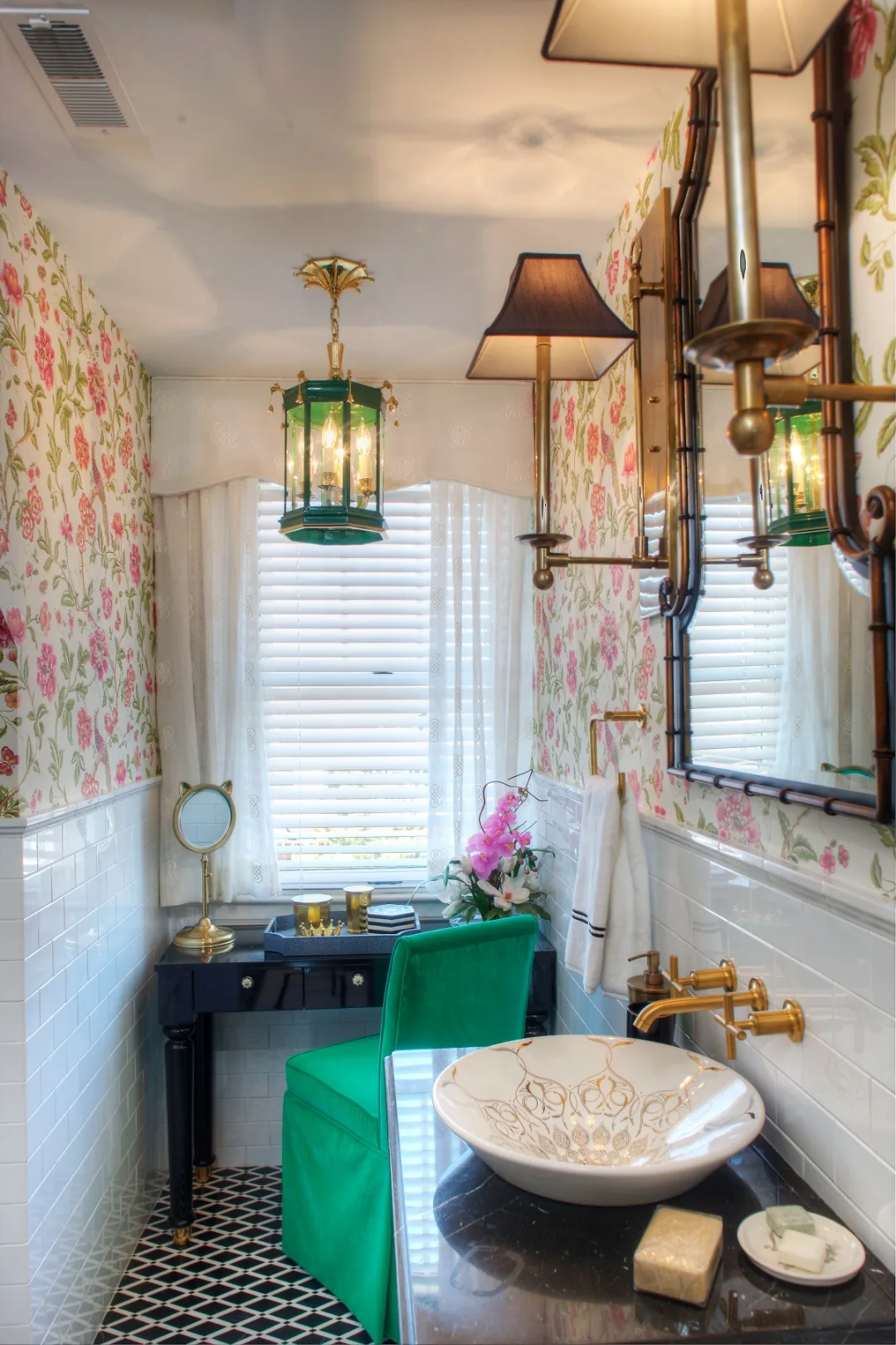 Cape May chinoiserie bathroom vanity vignette with a green glass lantern, brass bamboo mirror and sconces, a green velvet skirted chair, and a gold-filigree vessel sink on a black lacquer console