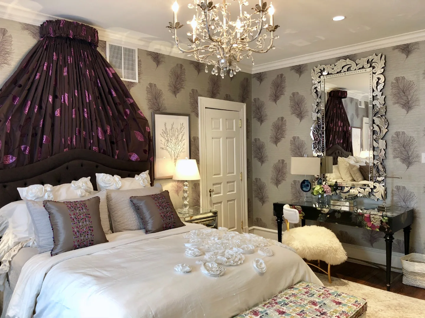 Wide view of the Cape May ensuite bedroom showing the draped bed crown, crystal chandelier, Venetian mirror, and mirrored vanity