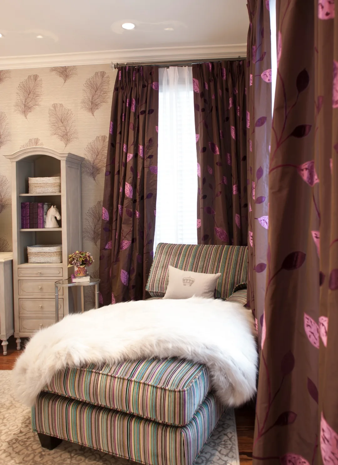 Multicolor striped chaise with a white sheepskin throw beneath leaf-print curtains and a fashion illustration in the Cape May ensuite