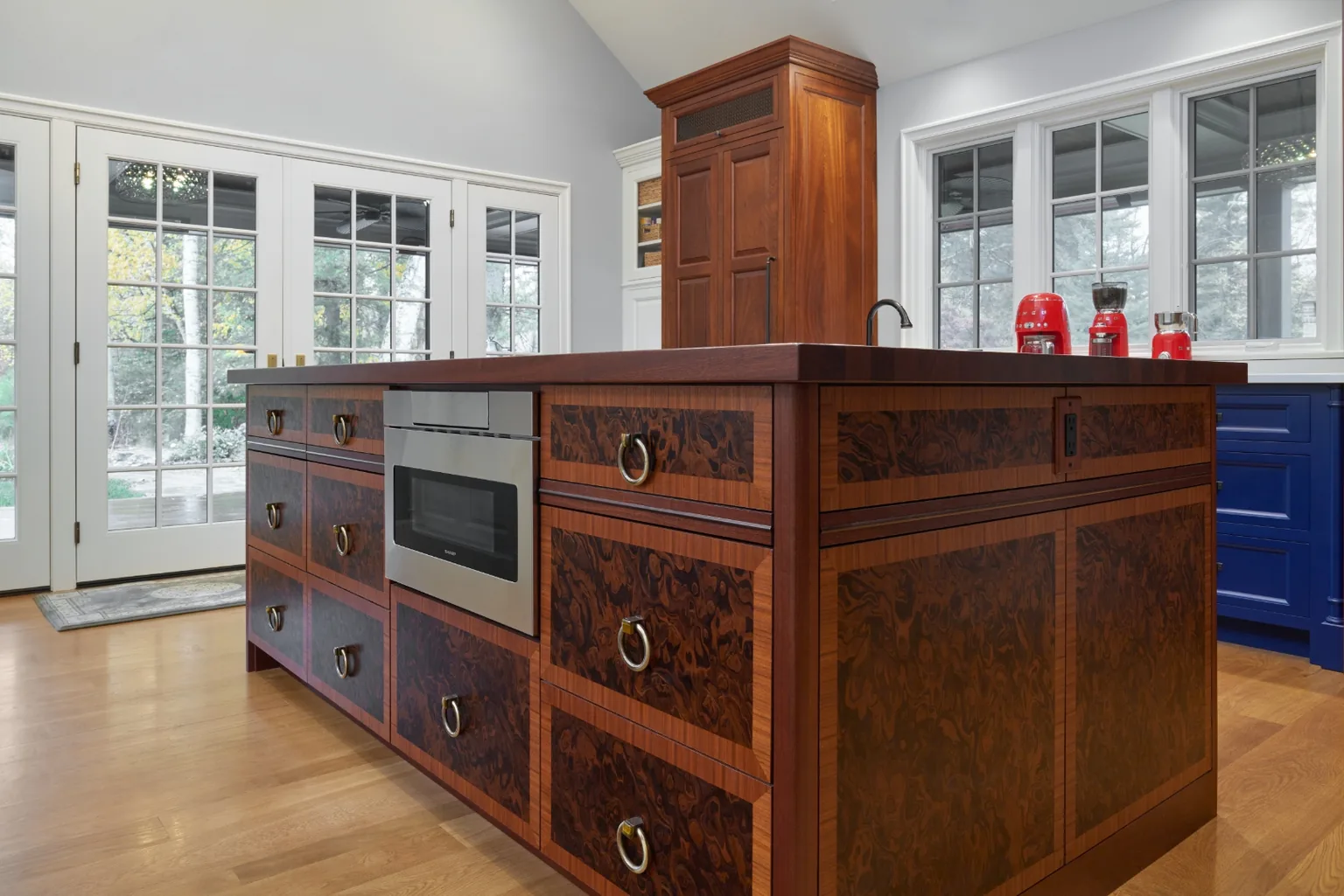 Furniture-grade burlwood island with banded inlay and brass ring pulls in a Chester, PA luxury kitchen