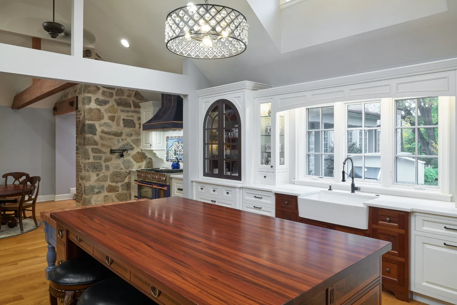Vaulted Chester kitchen with a crystal drum pendant, skylight, exposed stone wall, and a farmhouse sink under bright windows