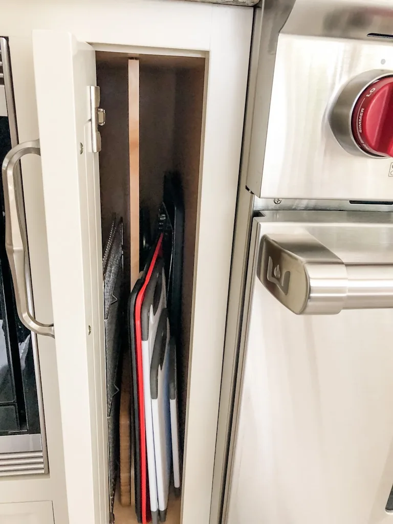 Vertical pull-out cabinet with wood dividers organizing baking sheets and cutting boards beside the stainless Wolf range in the Churchville kitchen