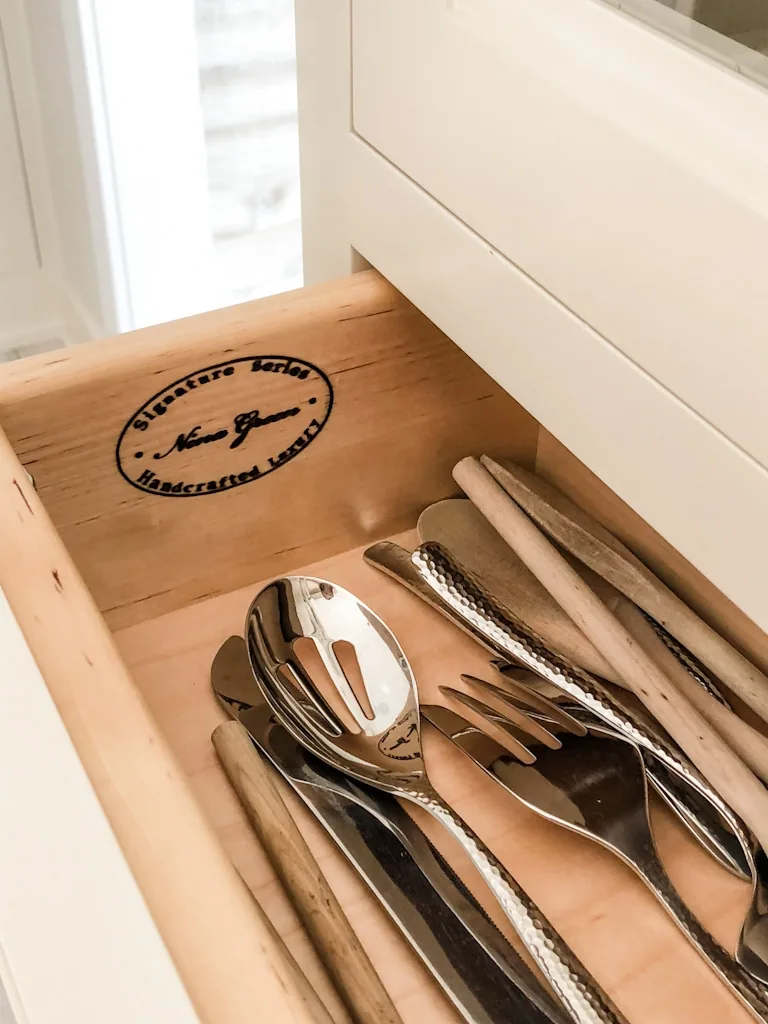 Detail of the Nina Green Signature Series Handcrafted Luxury stamp branded inside a custom dovetailed wood flatware drawer in the Churchville kitchen