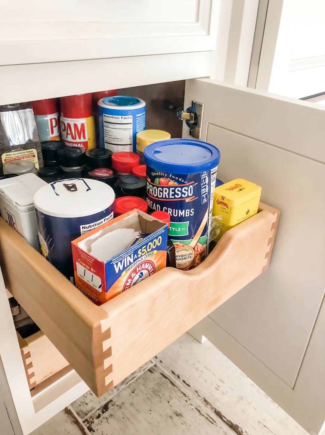 Custom dovetailed wood pull-out spice and pantry drawer stocked with canisters and tins beneath a granite counter in the Churchville kitchen