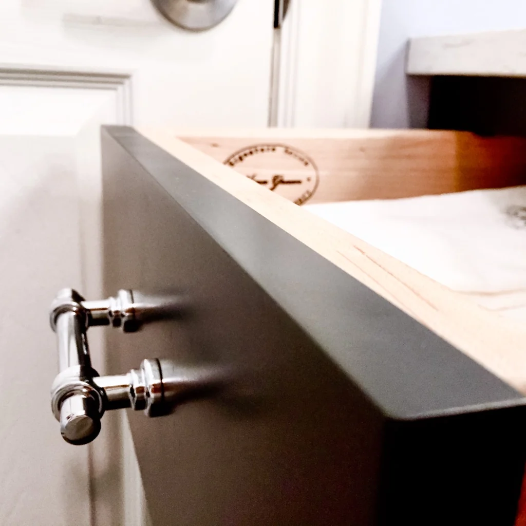 Open vanity drawer in the Holland bathroom revealing the dovetailed solid-wood drawer box branded with the Nina Green Signature Series maker’s stamp