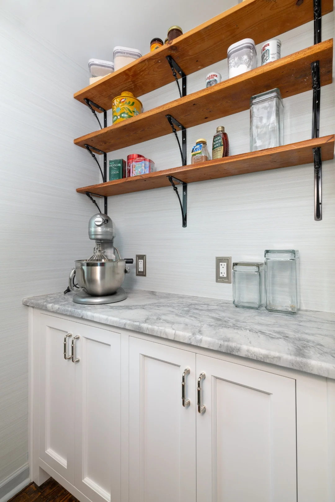 Richboro pantry corner with white base cabinets, a marble counter holding a stand mixer and glass canisters, and reclaimed-wood open shelves on iron brackets