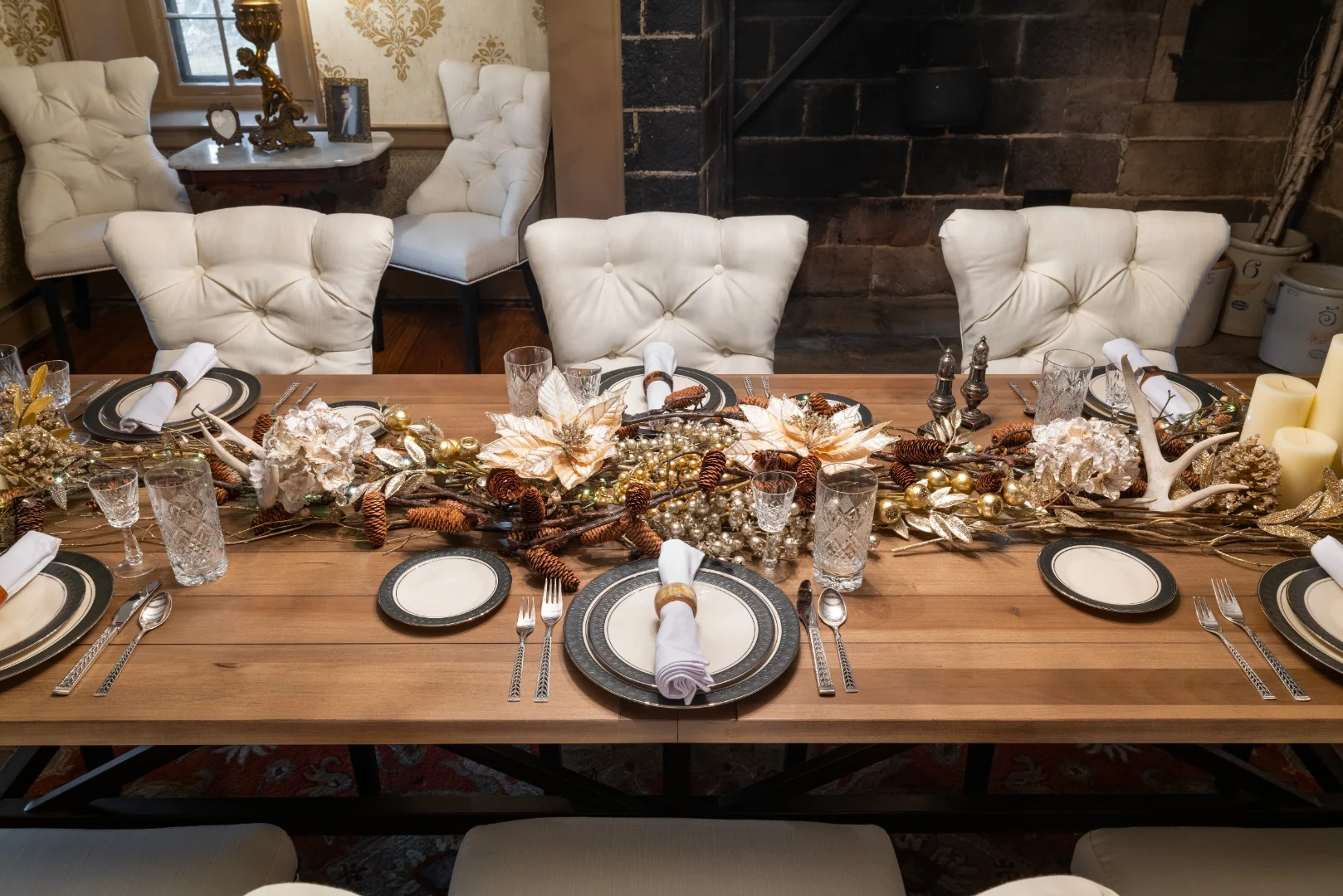 Overhead view of the formal place settings and a gold-and-pinecone centerpiece runner down the wood trestle table in the Southampton dining room